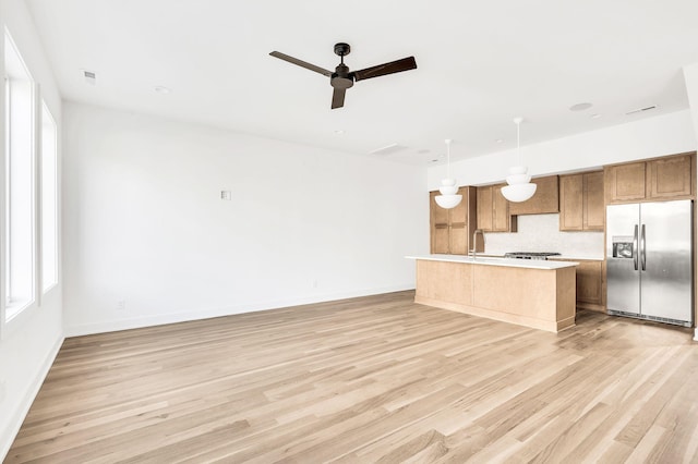 kitchen with hanging light fixtures, a kitchen island, a wealth of natural light, and stainless steel fridge