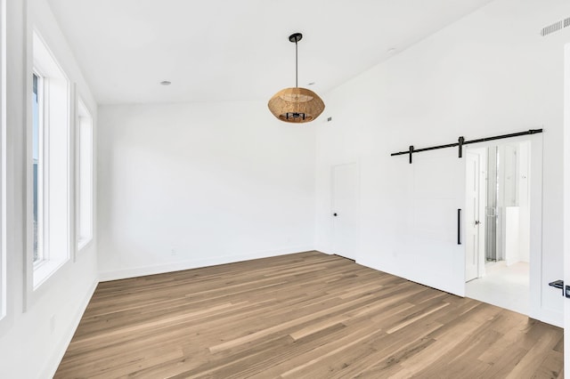 empty room featuring hardwood / wood-style flooring, a barn door, and a towering ceiling