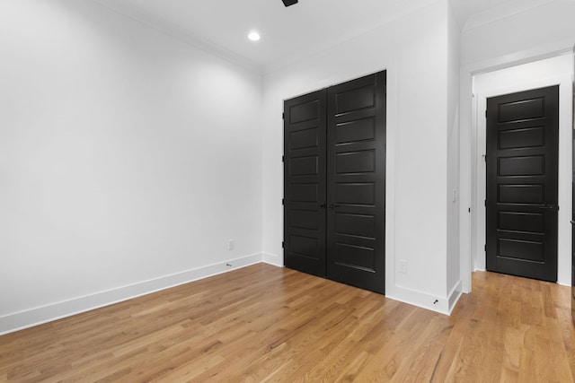 unfurnished bedroom with crown molding, a closet, and light wood-type flooring