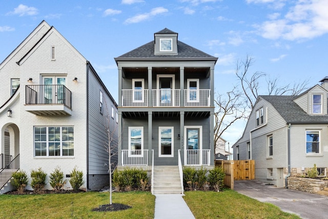 view of front of house with a porch, a balcony, and a front lawn