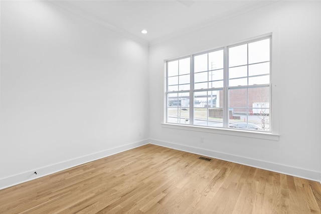 unfurnished room with ornamental molding and light wood-type flooring