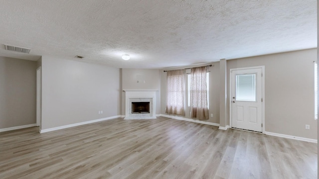 unfurnished living room featuring a textured ceiling and light wood-type flooring