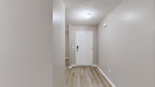 doorway to outside with light hardwood / wood-style floors and a textured ceiling