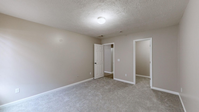 unfurnished bedroom with light colored carpet and a textured ceiling