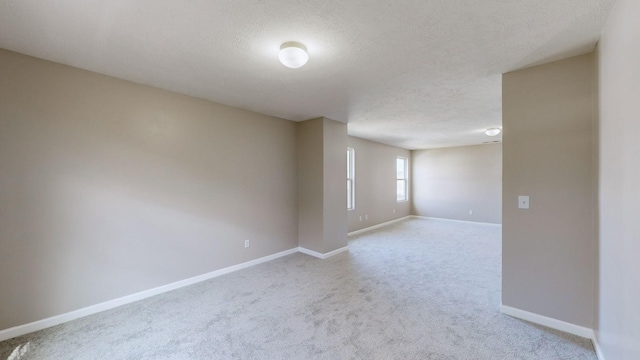 spare room with light carpet and a textured ceiling