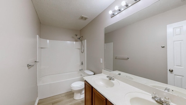 full bathroom with  shower combination, hardwood / wood-style floors, vanity, a textured ceiling, and toilet