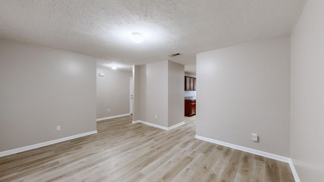 spare room featuring light hardwood / wood-style floors and a textured ceiling