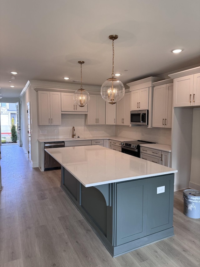 kitchen with a kitchen island, pendant lighting, stainless steel appliances, decorative backsplash, and white cabinets