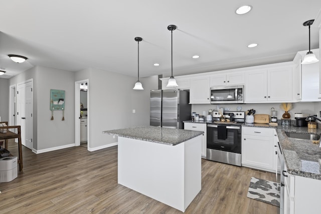 kitchen with sink, a center island, pendant lighting, stainless steel appliances, and white cabinets