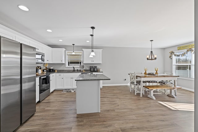 kitchen with hardwood / wood-style floors, pendant lighting, white cabinets, a center island, and stainless steel appliances