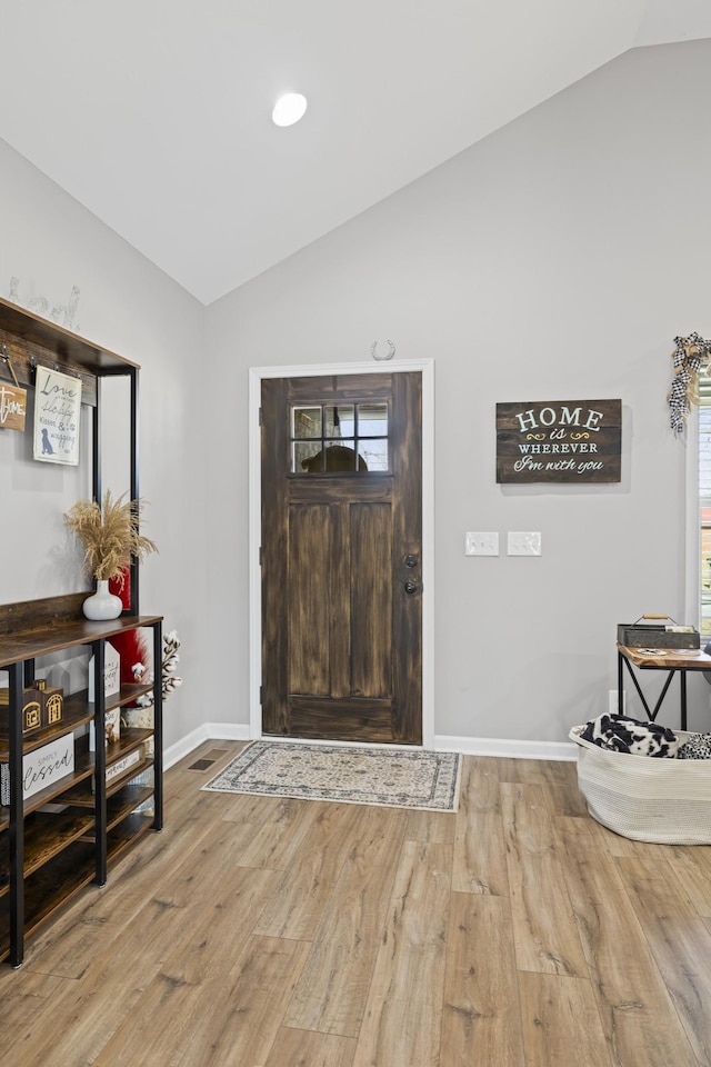 foyer entrance with hardwood / wood-style flooring, vaulted ceiling, and plenty of natural light