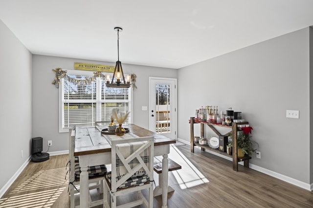 dining space featuring wood-type flooring and an inviting chandelier