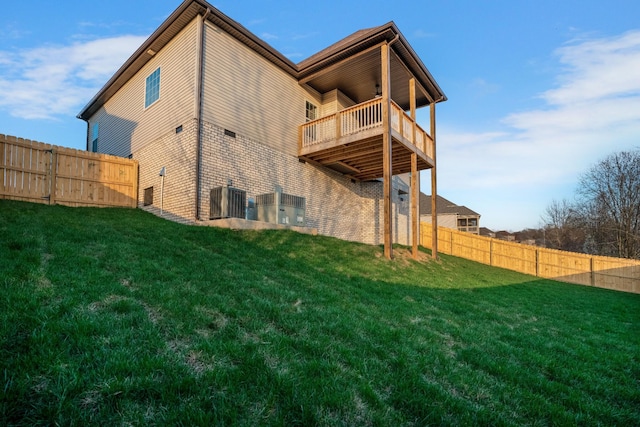 rear view of property with a balcony, central AC unit, and a lawn