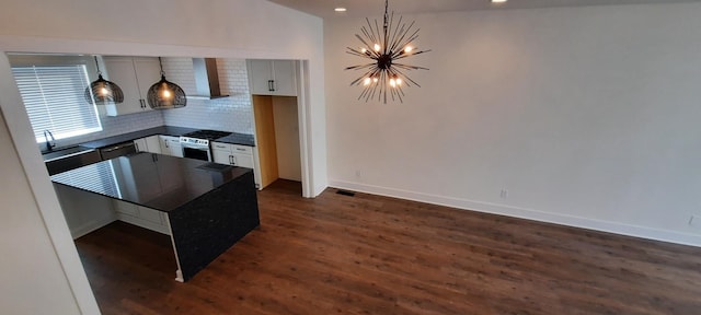 kitchen featuring wall chimney exhaust hood, a chandelier, dark hardwood / wood-style floors, stainless steel appliances, and backsplash