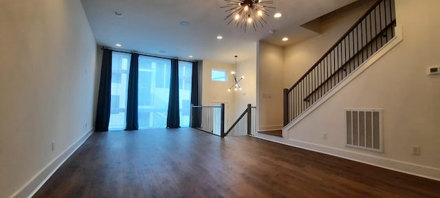 spare room featuring an inviting chandelier, dark hardwood / wood-style flooring, and expansive windows