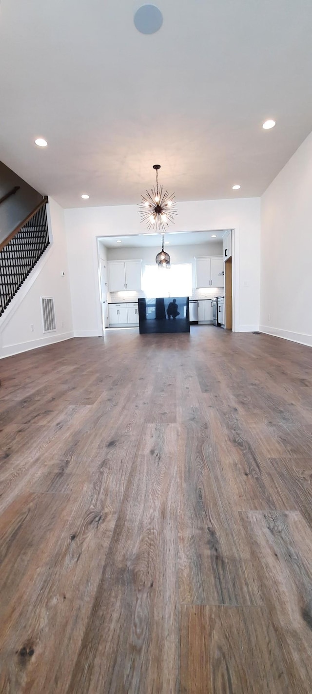 unfurnished living room featuring dark wood-type flooring and a notable chandelier