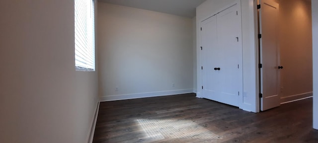 unfurnished bedroom with dark wood-type flooring and a closet