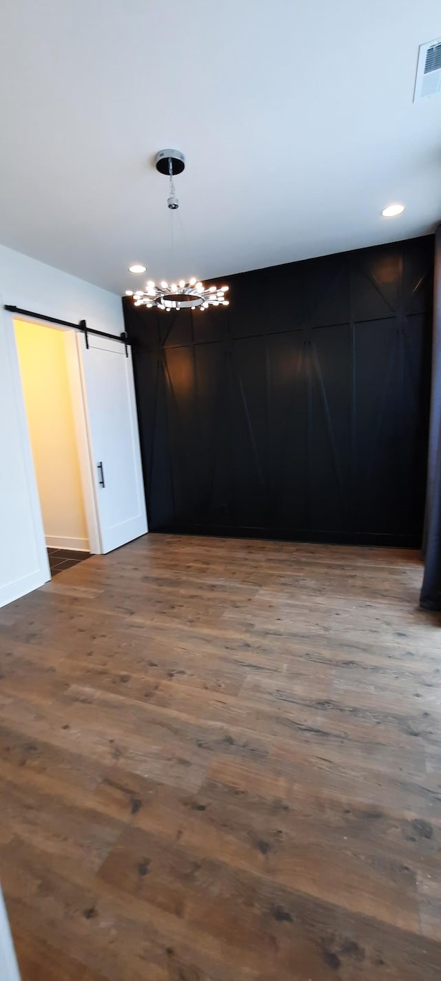 empty room featuring a barn door and dark hardwood / wood-style flooring