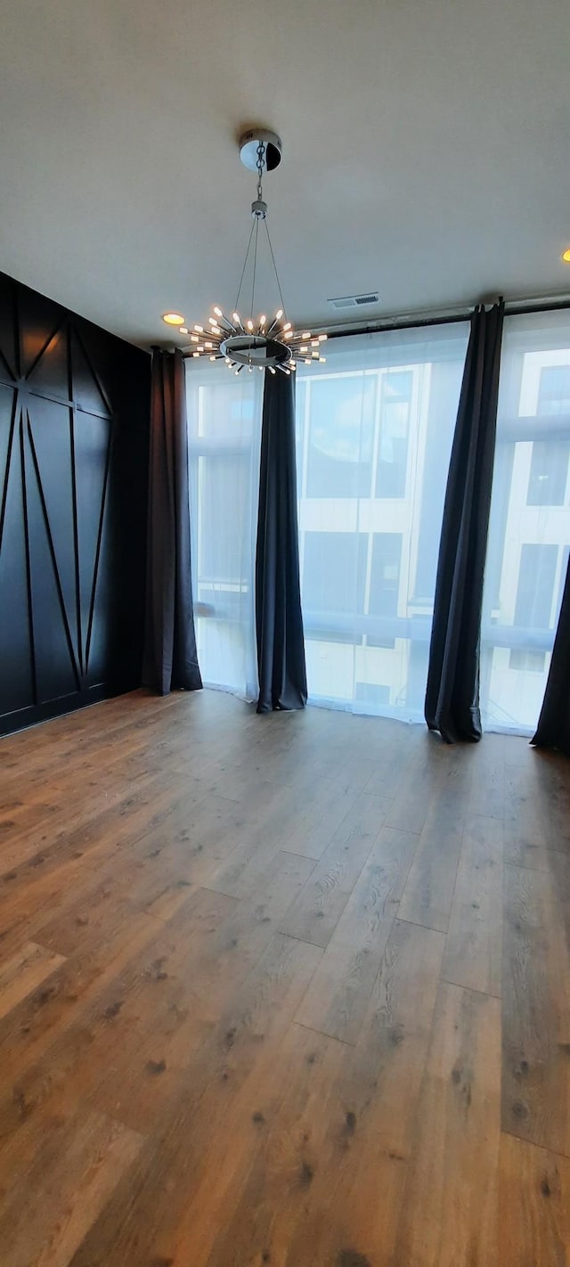 unfurnished dining area featuring a notable chandelier and wood-type flooring