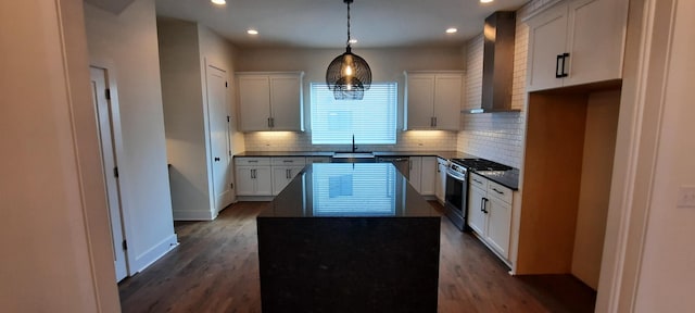 kitchen with pendant lighting, sink, white cabinets, a center island, and stainless steel gas range oven