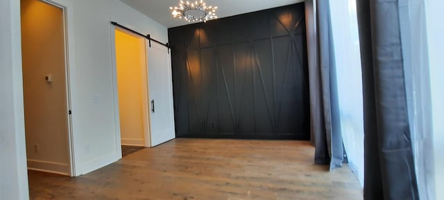 corridor featuring a barn door, a chandelier, and hardwood / wood-style floors