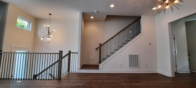 staircase featuring hardwood / wood-style floors, a chandelier, and a high ceiling