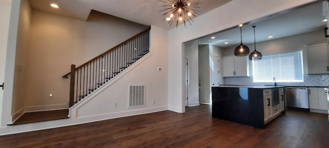 kitchen with white cabinetry, hanging light fixtures, dark wood-type flooring, and stainless steel dishwasher