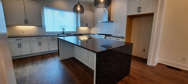 kitchen with a kitchen island, decorative light fixtures, sink, dark hardwood / wood-style flooring, and wall chimney exhaust hood