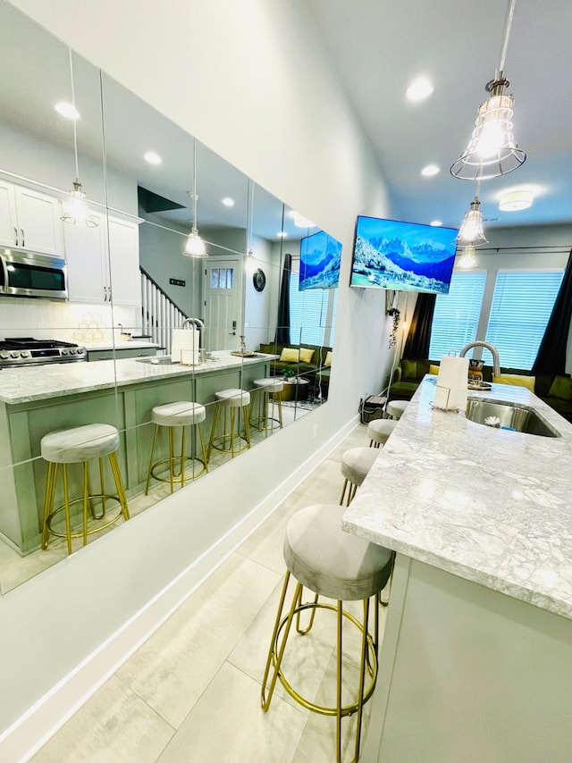 kitchen featuring pendant lighting, a breakfast bar, white cabinets, and appliances with stainless steel finishes