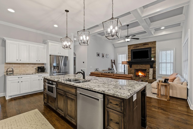 kitchen with stainless steel appliances, sink, hanging light fixtures, and white cabinets