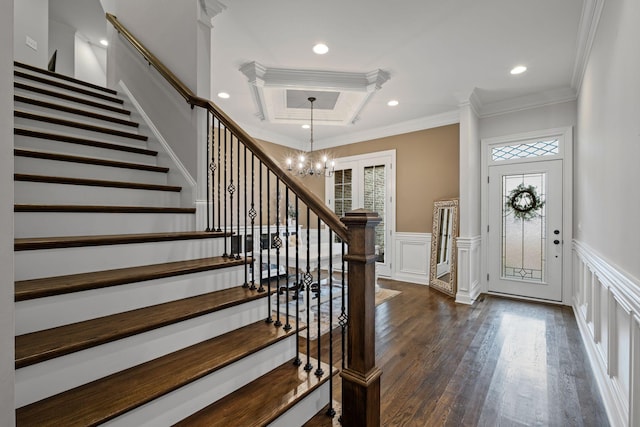 entrance foyer with dark wood-type flooring, ornamental molding, plenty of natural light, and a chandelier