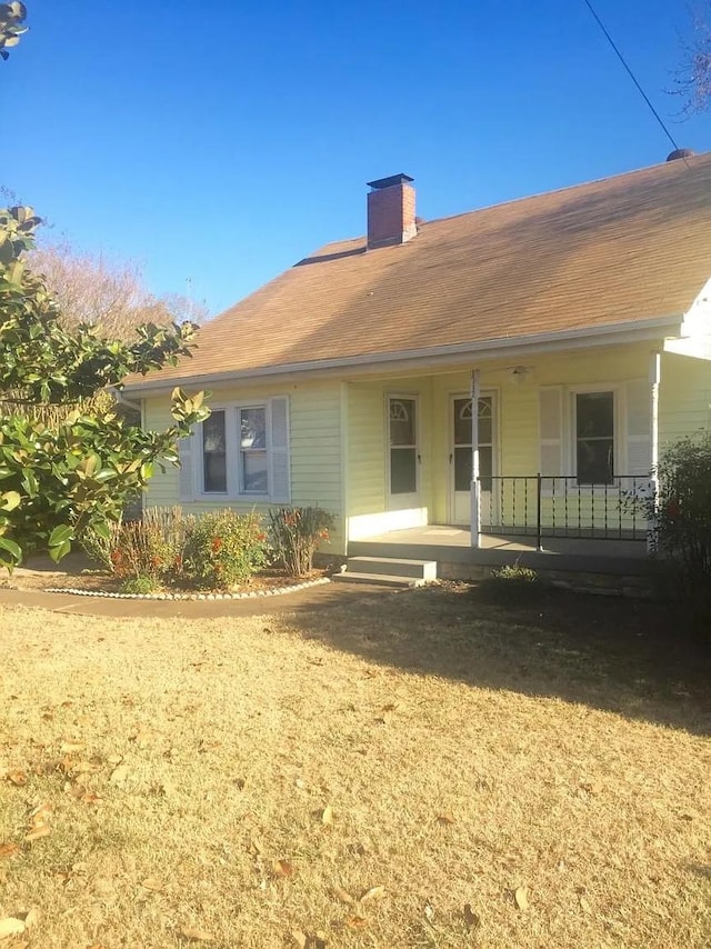 rear view of house featuring a porch and a yard