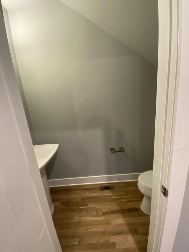 bathroom featuring lofted ceiling, wood-type flooring, and toilet