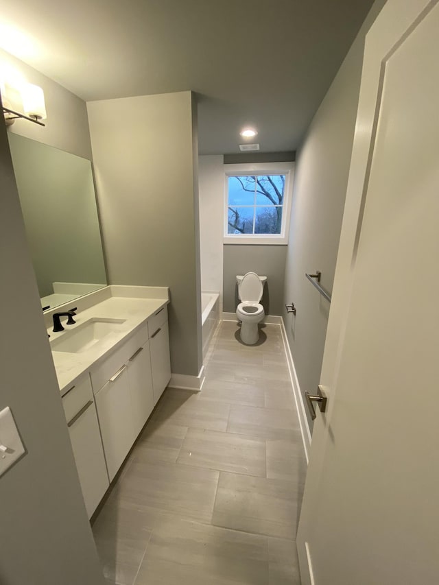 bathroom with vanity, a bathing tub, and toilet