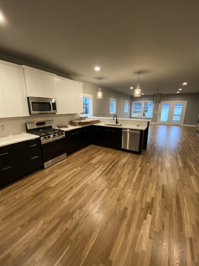 kitchen with pendant lighting, white cabinetry, stainless steel appliances, and sink