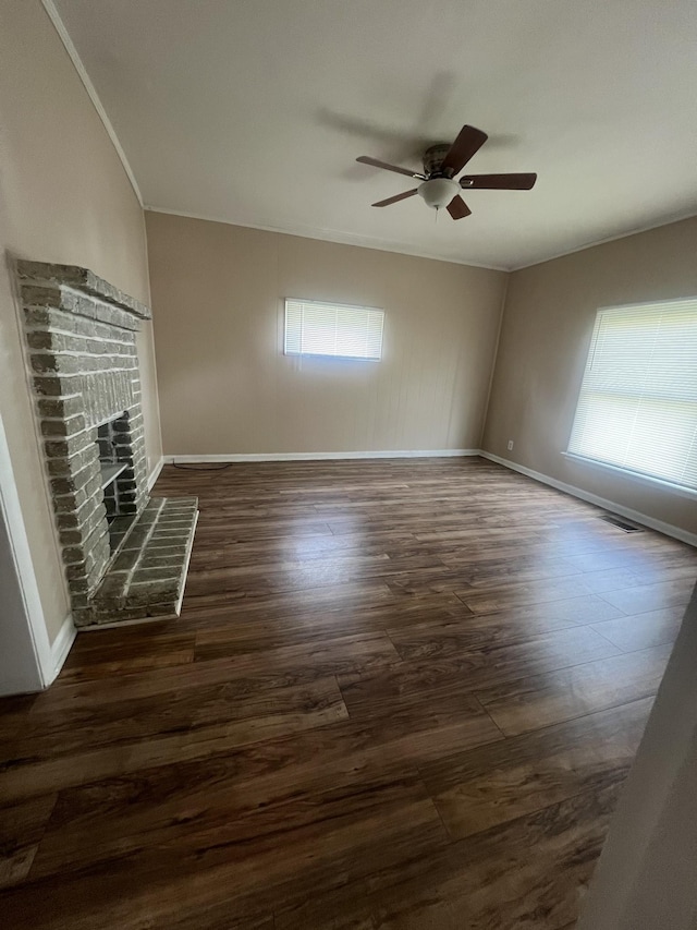 unfurnished living room featuring ceiling fan, ornamental molding, a fireplace, and dark hardwood / wood-style flooring