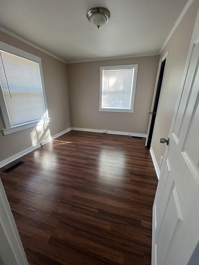 empty room with ornamental molding and dark hardwood / wood-style flooring