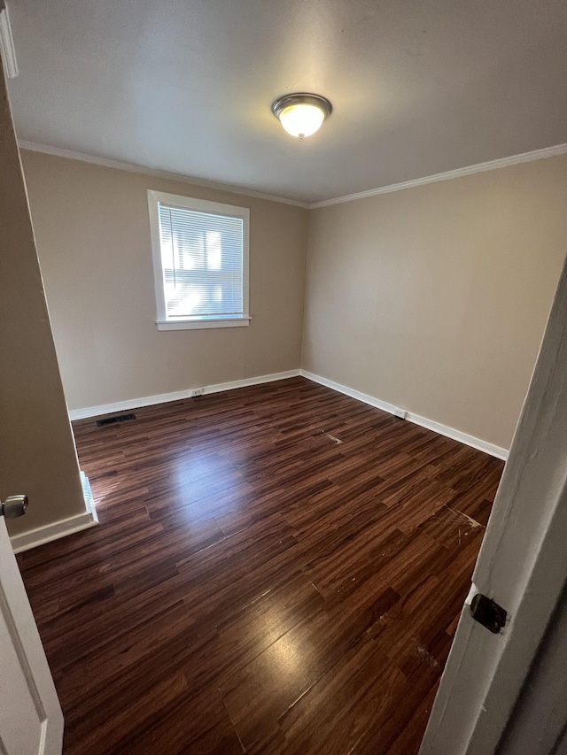 spare room featuring crown molding and dark hardwood / wood-style flooring