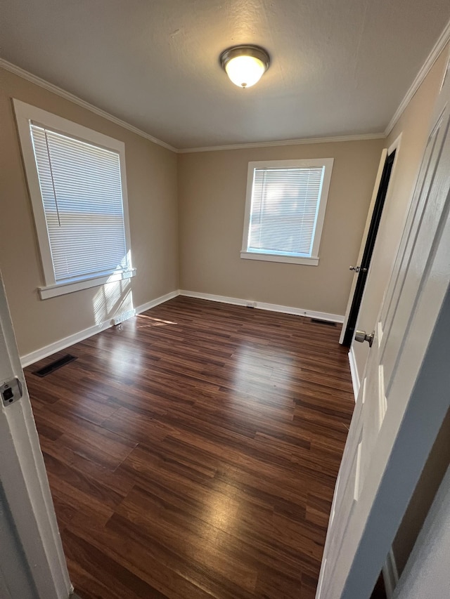 empty room featuring dark wood-type flooring and ornamental molding