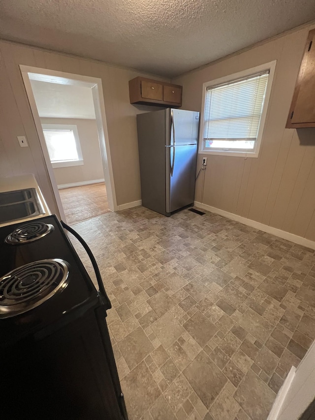 kitchen with sink, a textured ceiling, stainless steel refrigerator, and black / electric stove