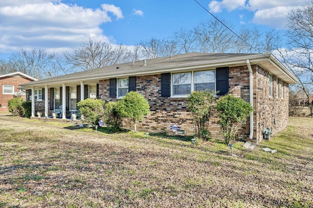 ranch-style house featuring covered porch and a front lawn