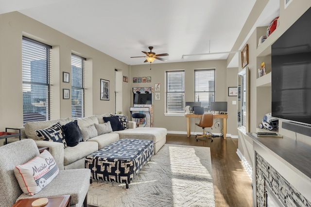 living area featuring a ceiling fan, baseboards, and wood finished floors