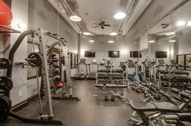 exercise room with a ceiling fan and a towering ceiling