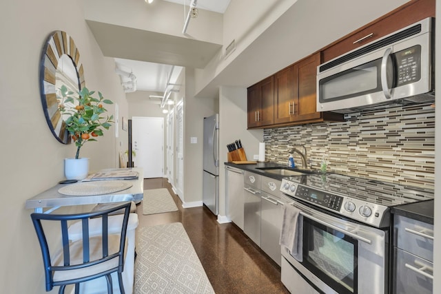 kitchen with tasteful backsplash, baseboards, dark countertops, appliances with stainless steel finishes, and a sink