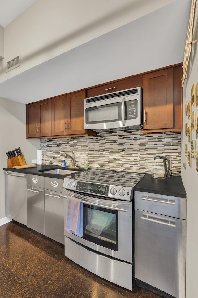 kitchen with stainless steel appliances, tasteful backsplash, dark countertops, and a sink