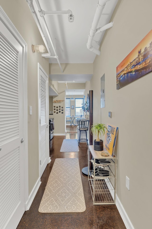 hallway featuring electric panel and baseboards