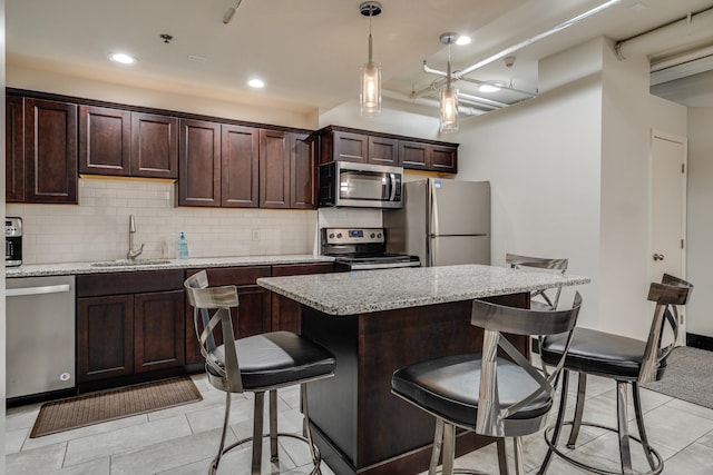 kitchen with stainless steel appliances, sink, a breakfast bar area, and light stone counters