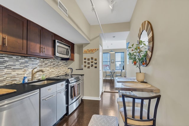 kitchen with sink, rail lighting, dark brown cabinets, stainless steel appliances, and decorative backsplash