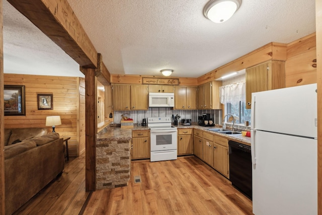 kitchen featuring wood walls, sink, white appliances, a textured ceiling, and light hardwood / wood-style flooring