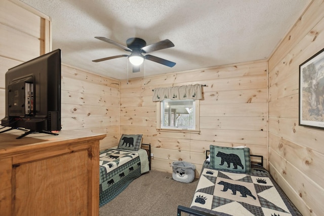 bedroom with ceiling fan, wooden walls, carpet flooring, and a textured ceiling